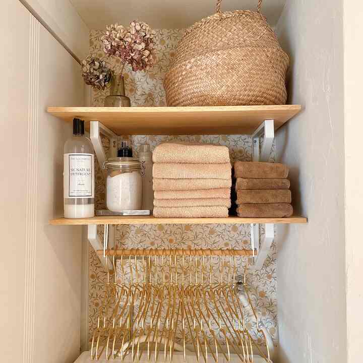 自然なナチュラルカラーと木目調が調和したトイレの棚に整頓されたタオルと洗剤が配置された雰囲気のあるインテリア
