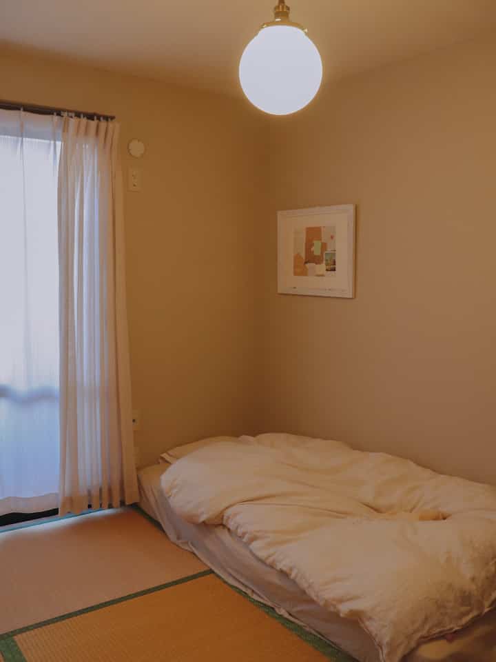 Beige-toned 6 tatami mat bedroom featuring tatami flooring and white duvet cover in a cozy setting