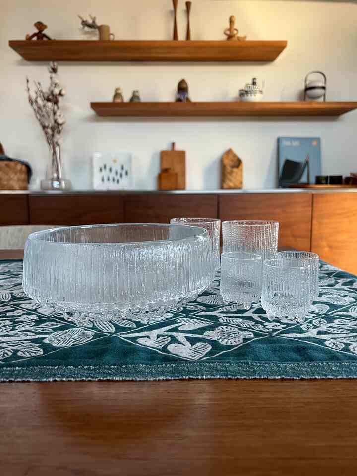 木目調と透明なガラス製品を中心とした北欧風のダイニング空間、自然で清潔感のある雰囲気