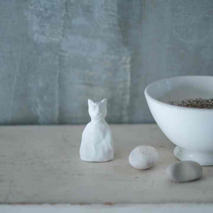 白を基調としたテーブルに猫のオブジェと器、石が配置されたミニマルなインテリア