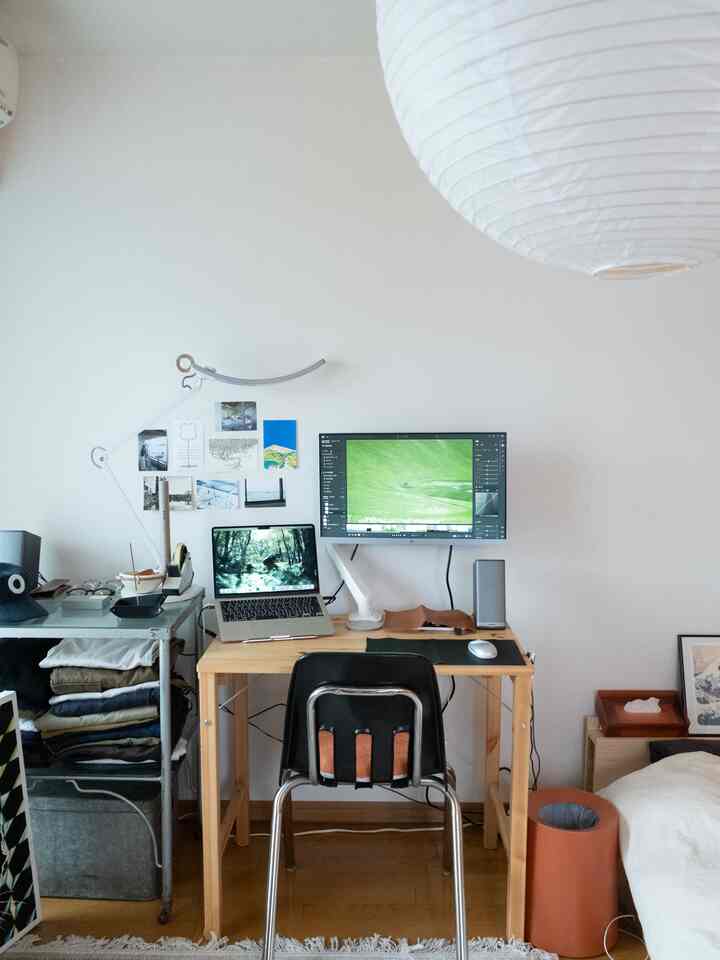 ナチュラルカラーの小さなワンルーム寝室兼ホームオフィス、ウッドデスクとパソコンが配置されたシンプルな空間