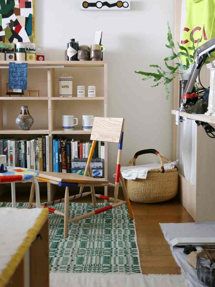 Natural tone living room featuring wooden bookshelf and chair with color accents in a clean space