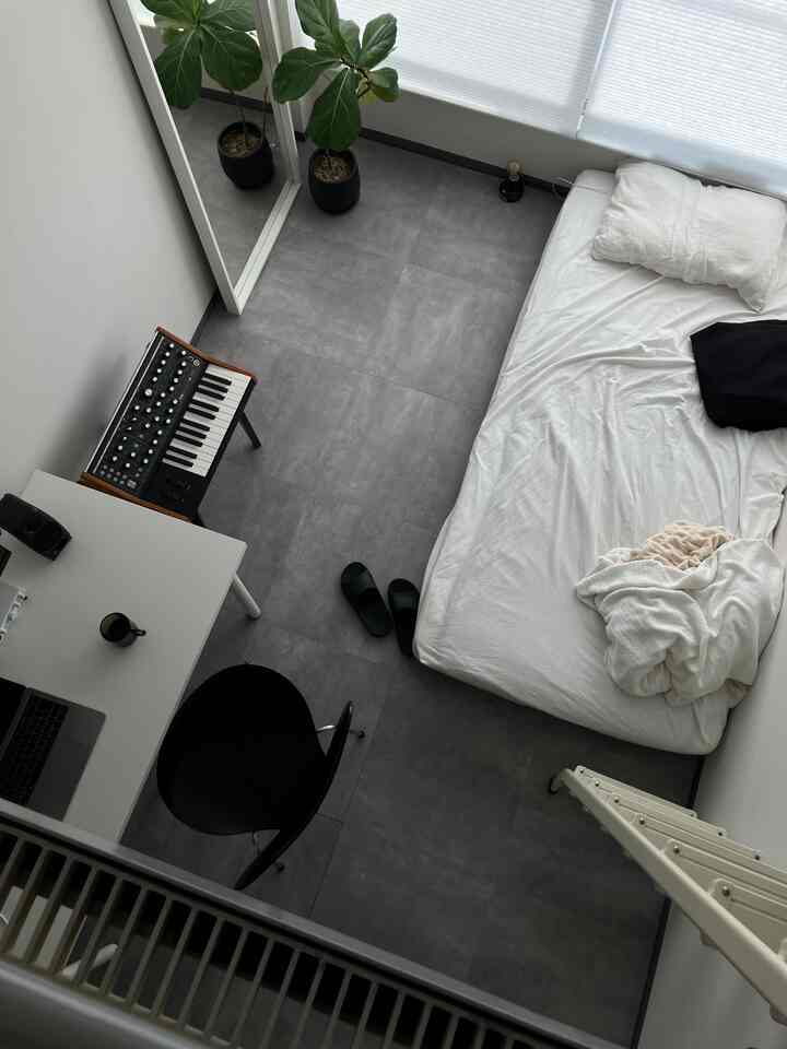 Modern single bedroom with gray flooring and white blinds, featuring a desk, office chair, and electronic keyboard in a neat setup
