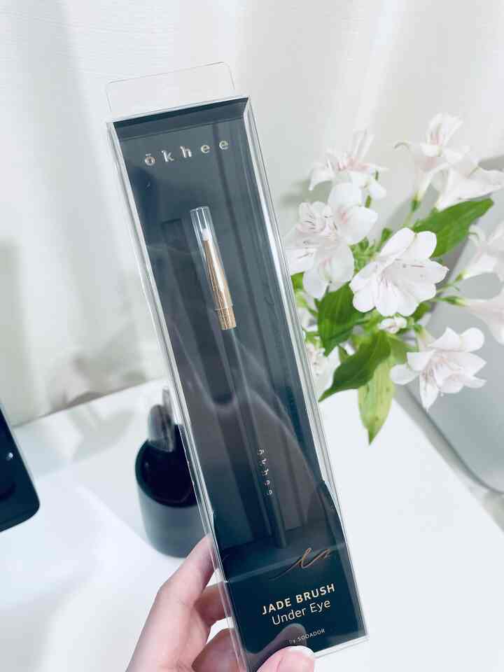 Simple black jade under-eye brush on a vanity table with white flowers arranged, creating a cozy atmosphere