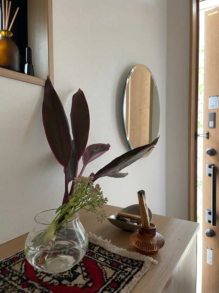 ナチュラルな木目調の玄関、ガラスの花瓶に植物が配置された雰囲気のあるインテリア