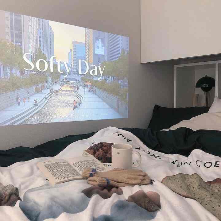 白と黒のトーンの寝室、壁にプロジェクター画面が映る雰囲気のあるインテリア