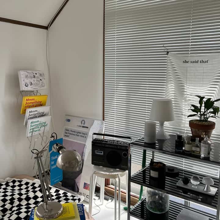 White and black toned bedroom featuring a mid-century modern stool with cassette player and modern storage shelves creating a stylish atmosphere