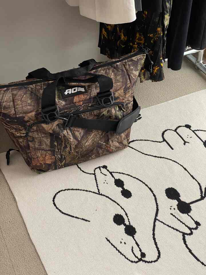 ベージュのカーペットの上に木柄のソフトクーラーと洋服掛けがある片付け途中のウォークインクローゼット