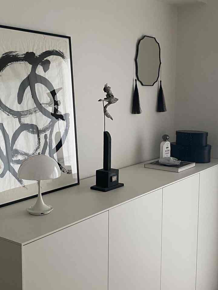 Monotone white and black living room featuring a floor lamp, abstract wall art, and a unique bird-shaped objet in a minimalist setting