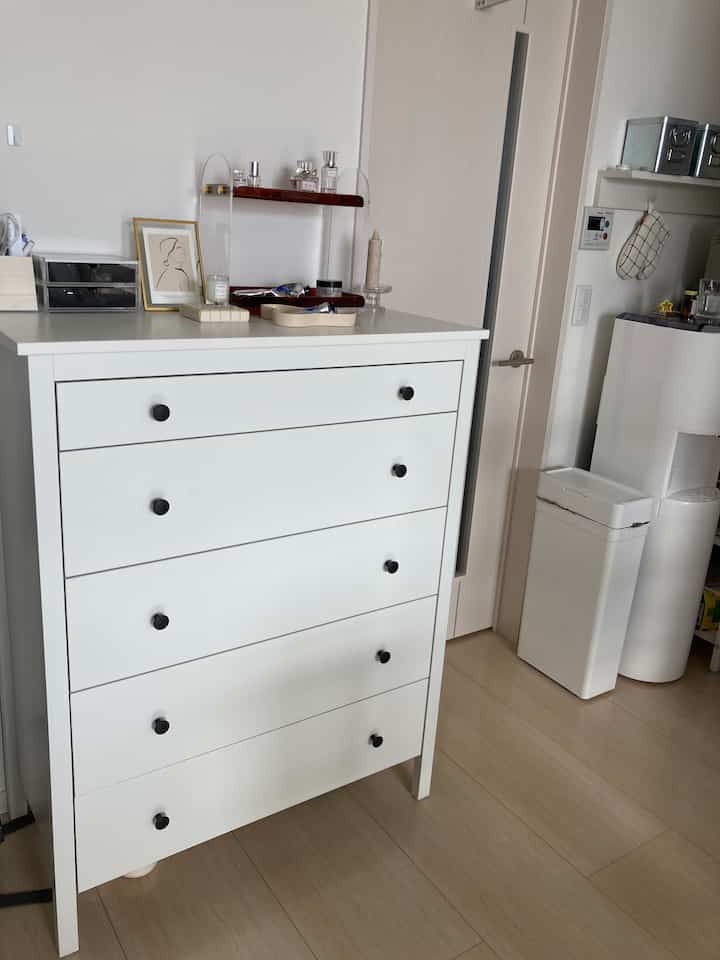 白とナチュラルウッド調が調和する狭いキッチン兼玄関スペースに配置された5段チェストと小物