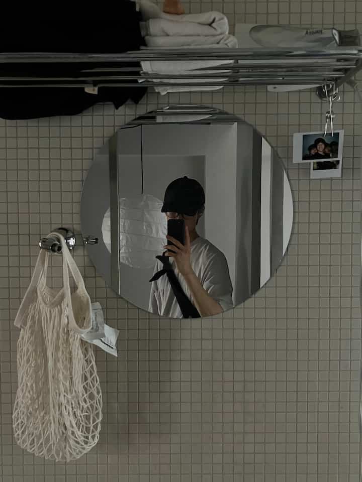 White tiled restroom with a round mirror and towel rack, featuring a simple and minimalistic atmosphere