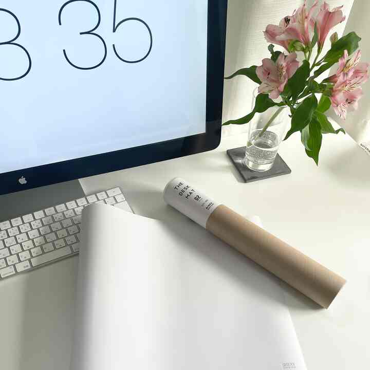 白を基調としたホームオフィス、コンピューターとデスクマットが配置されたシンプルな雰囲気のインテリア