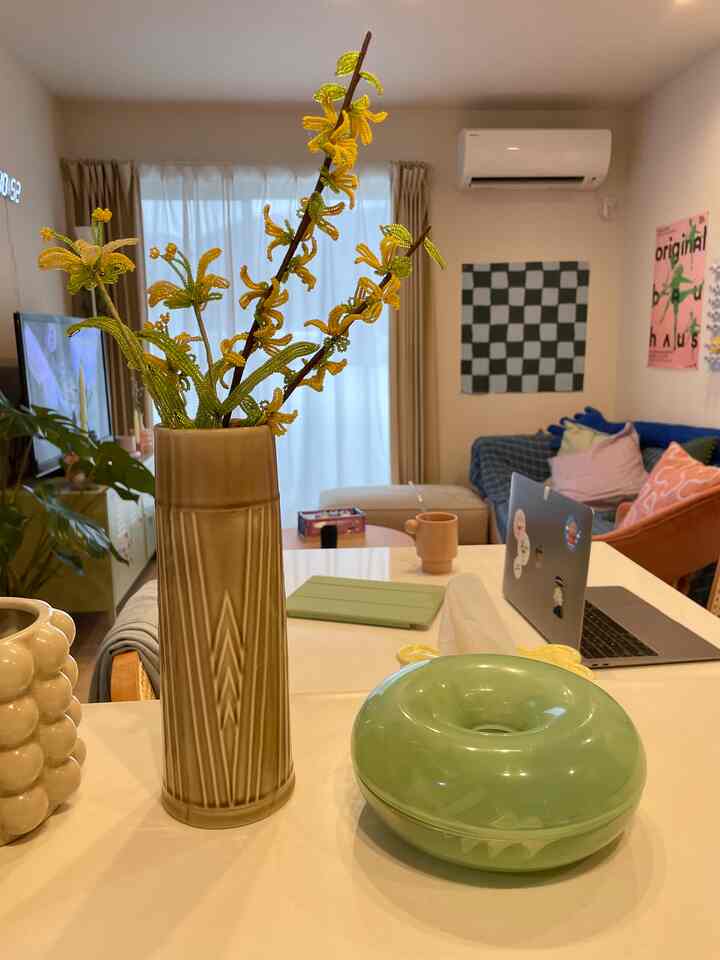 ベージュとホワイトのトーンのリビングとキッチン、花瓶とクッションが配置されたモダンな雰囲気のインテリア