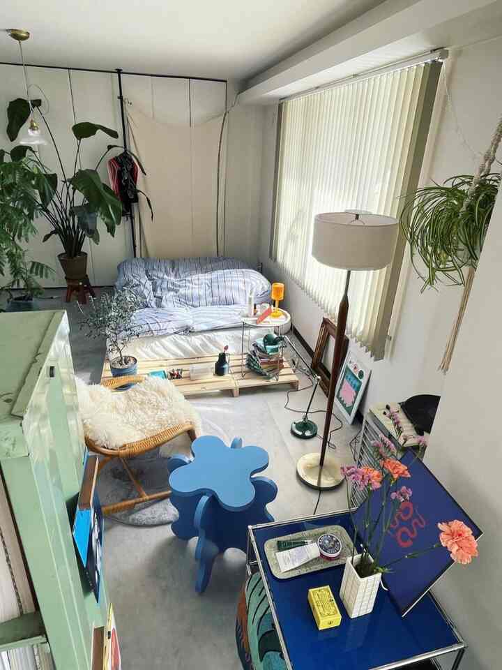 White and blue toned compact bedroom living space featuring floor lamp and plants with natural, simple atmosphere