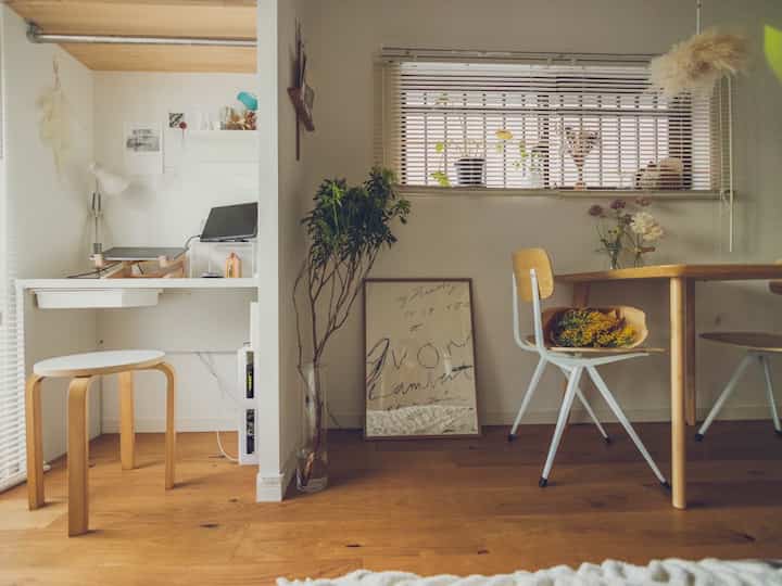 ホワイトの壁と木目調の床が特徴のリビング・ダイニングスペース、左側にホームオフィスが配置された落ち着いた雰囲気のインテリア