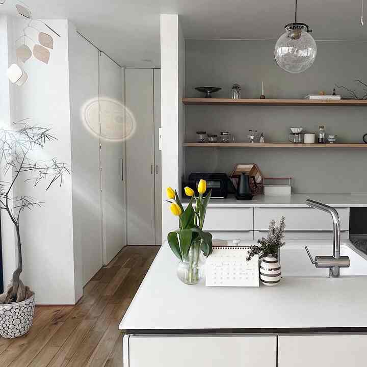 白とナチュラルの色調のキッチン、シンプルなデザインに黄色のチューリップの花瓶がアクセントの雰囲気あるインテリア