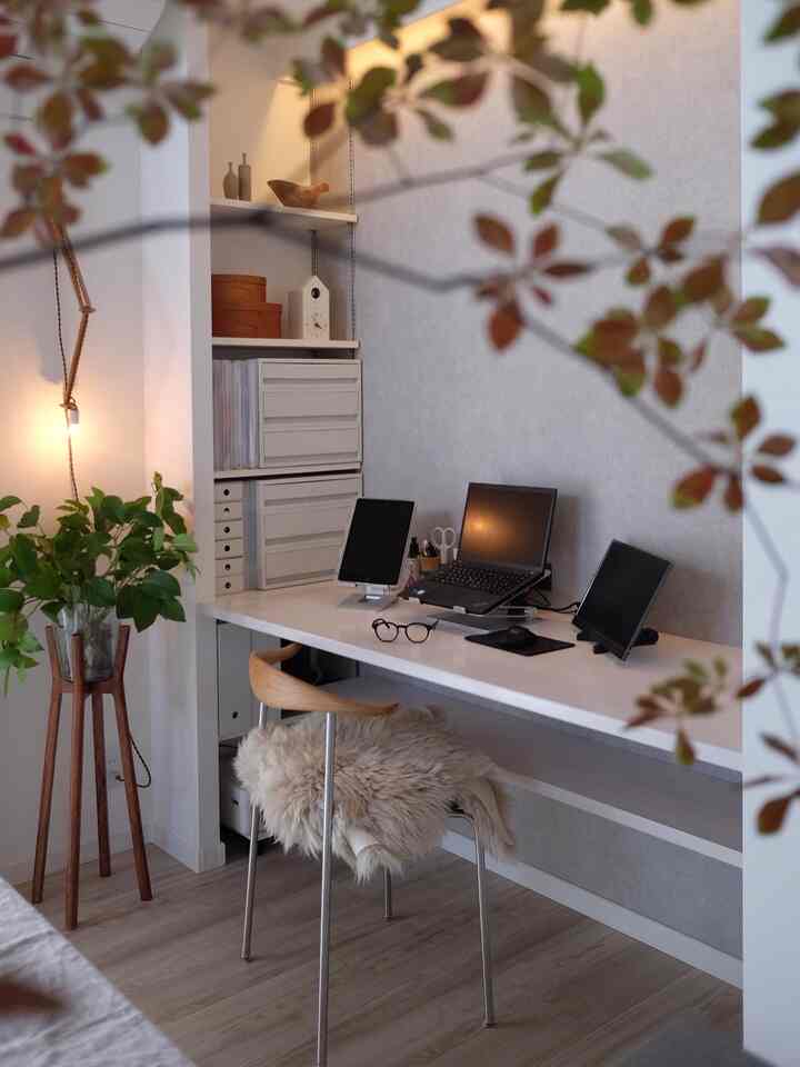 白と木目調のナチュラルな雰囲気のホームオフィスワークスペース、デスク上にノートパソコンとタブレットが配置された印象的な空間