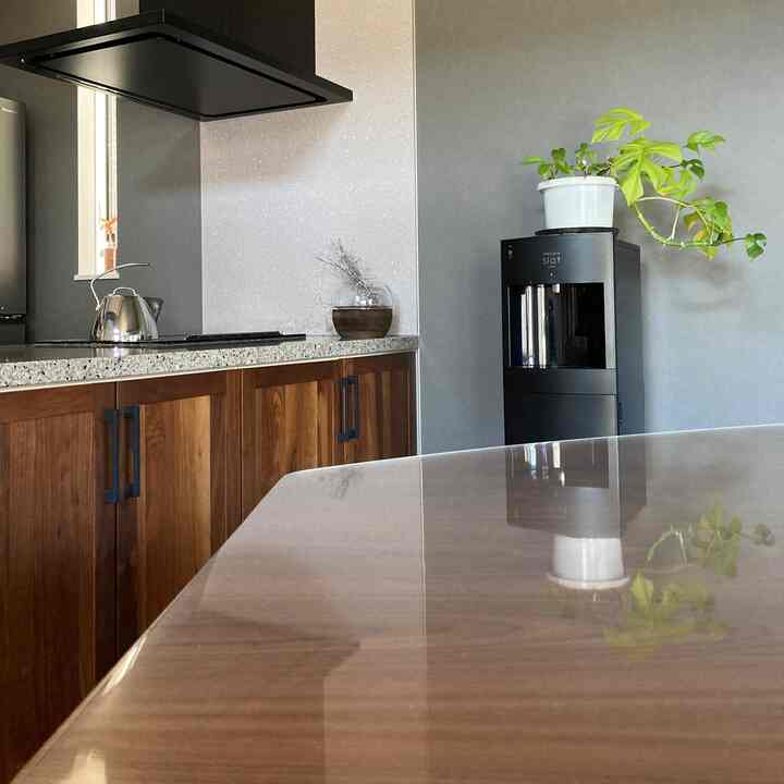 ブラウンの木目調のダイニングテーブルとグレーの壁が調和したモダンなキッチン空間