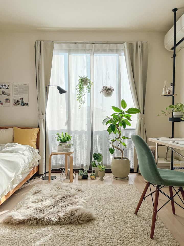 明るいホワイトとナチュラルカラーの寝室、スツールと多様な植物が配置された雰囲気のあるインテリア