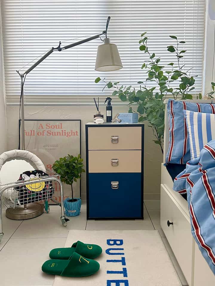 ナチュラルカラーとブルーのトーンの寝室、モノスクエア3段チェストが配置された清潔でモダンな雰囲気のインテリア