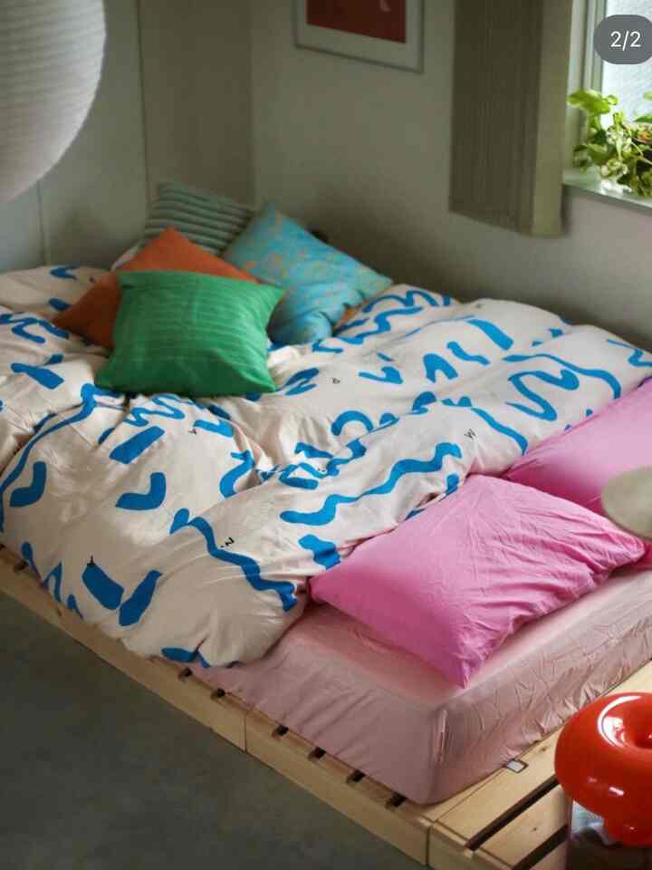 Pastel and natural tone bedroom featuring a cozy bed with multiple colored pillows creating a warm atmosphere