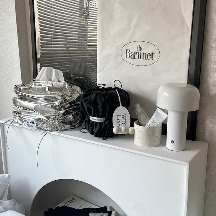 白を基調とした玄関空間、白いソファの肘掛けと黒いポーチが置かれたすっきりとしたインテリア