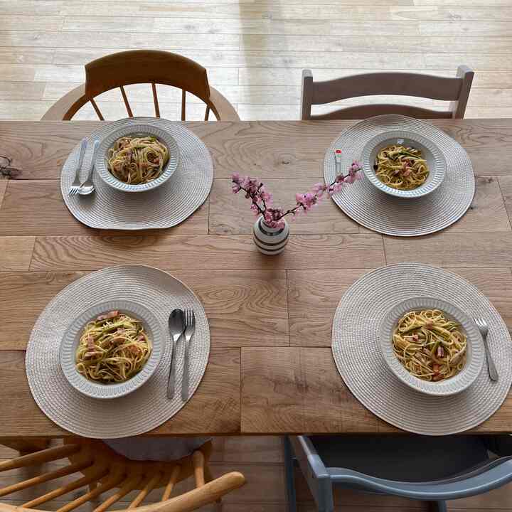 ナチュラルな木目調のキッチンダイニング、4脚のダイニングチェアとピンクの花瓶が置かれた温かみのある家族の昼食空間