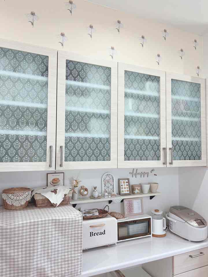 ベージュとホワイトの色調のキッチン、チェック柄の布とかご収納が配置された自然で温かみのあるインテリア