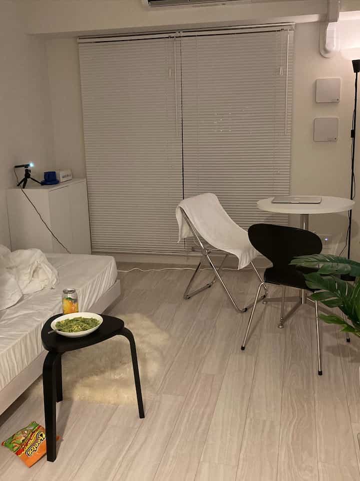 A white and gray toned 1K 8-tatami room featuring minimal furniture layout and a quiet modern atmosphere