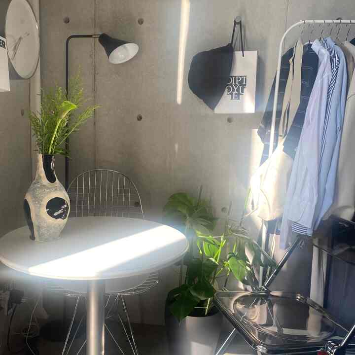 白と緑のトーンが調和するモダンなリビングコーナー、丸いダイニングテーブルと椅子、緑の植物が配置された空間