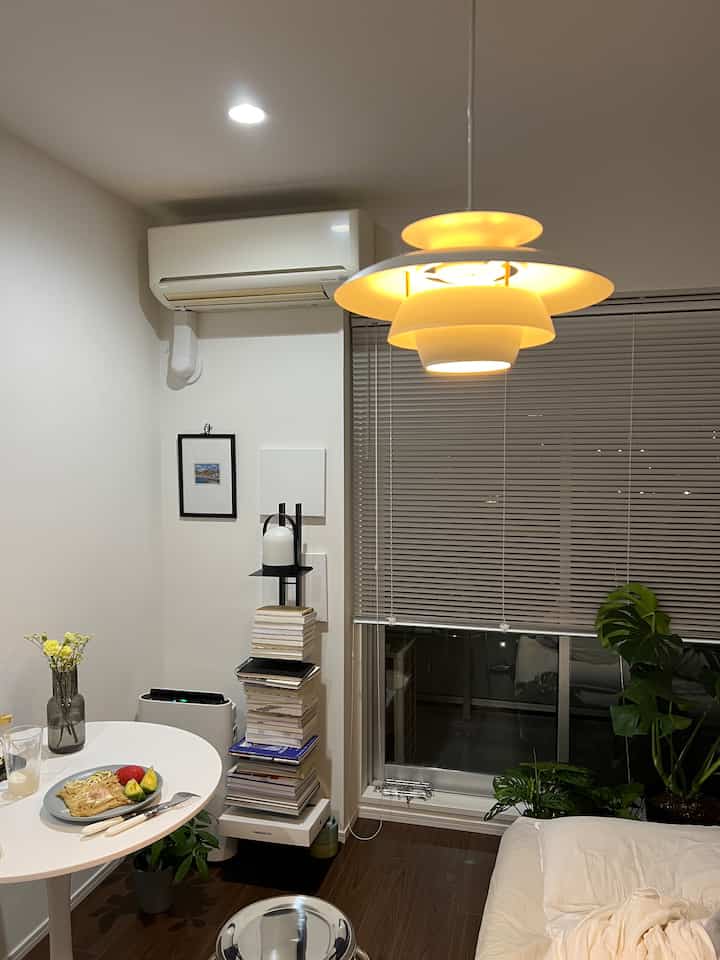 白と木目調の調和が取れた一人暮らしの部屋、ペンダントライトと丸テーブル、ソファが配置された雰囲気のあるカフェ風インテリア