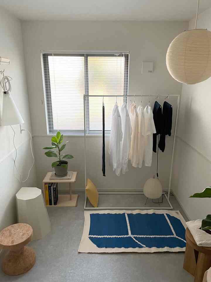 白とネイビーのトーンが特徴的なミニマルなリビング、模様のあるラグと植物が配置された明るくすっきりしたインテリア