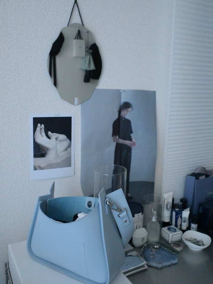 Soft beige-walled single household vanity space featuring a blue handbag and makeup items