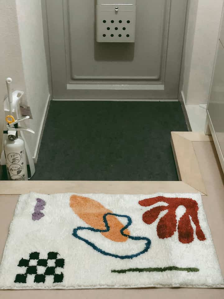 Modern entrance featuring a bright white carpet with orange and red abstract patterns, placed at the doorway