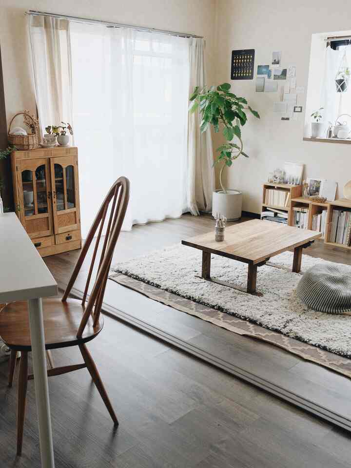 ナチュラルカラーと木目調の1LDKリビング、中央に木製テーブルとラグが配置された雰囲気のある空間