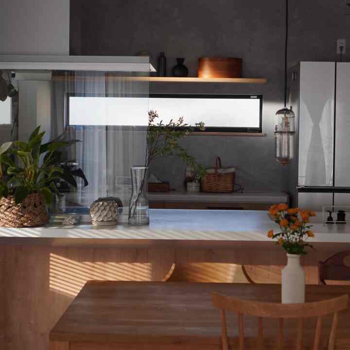 木目調と白が調和したダイニング、ダイニングテーブルと花瓶、植物が配置され、自然な雰囲気のあるインテリア