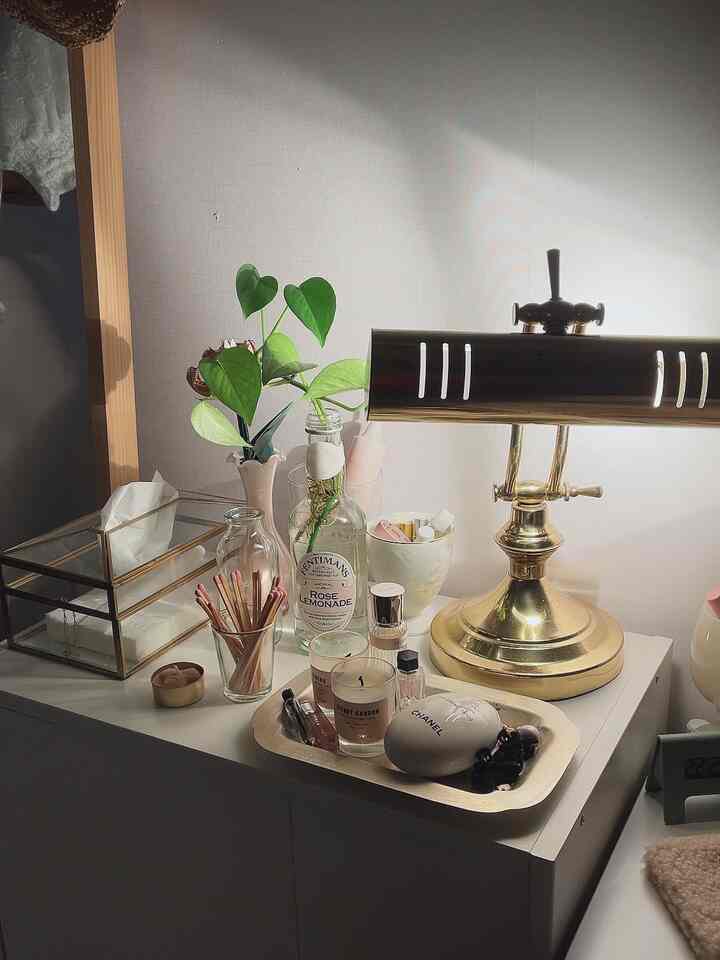 ホワイトとゴールドの色調の化粧台、植物とテーブルランプが配置された雰囲気のある空間