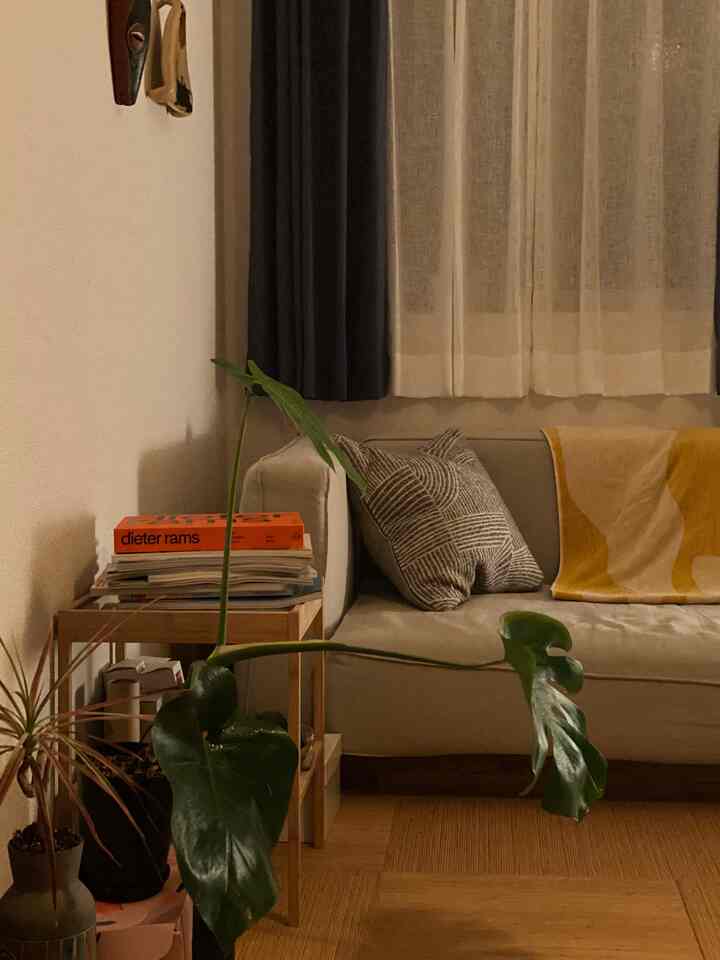 ナチュラルな木目調とグレーのソファとナイトテーブル、イエローのブランケットがアクセントの居心地の良いリビング