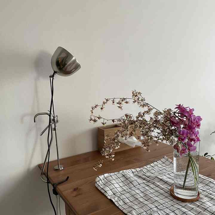 ナチュラルカラーのキッチン、木目調のテーブルに花瓶とチェック柄のテーブルランナーが配置された雰囲気のある空間