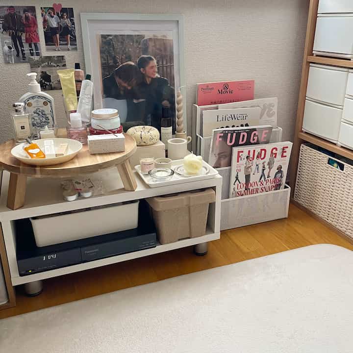 Cozy corner space in bright white and natural brown tones featuring magazine rack, candles, and wooden table