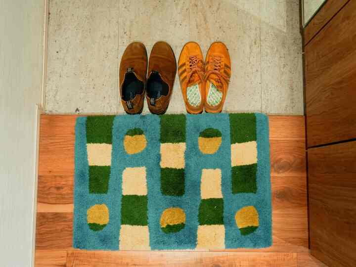 Cozy entrance space featuring a brown and green entrance mat on a wooden floor with shoes neatly placed above it
