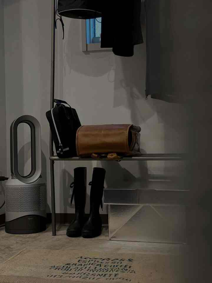 シルバーとブラックの色調の玄関スペース、ベンチと収納ボックス、ブーツが配置された整然とした収納アイデアのあるインテリア