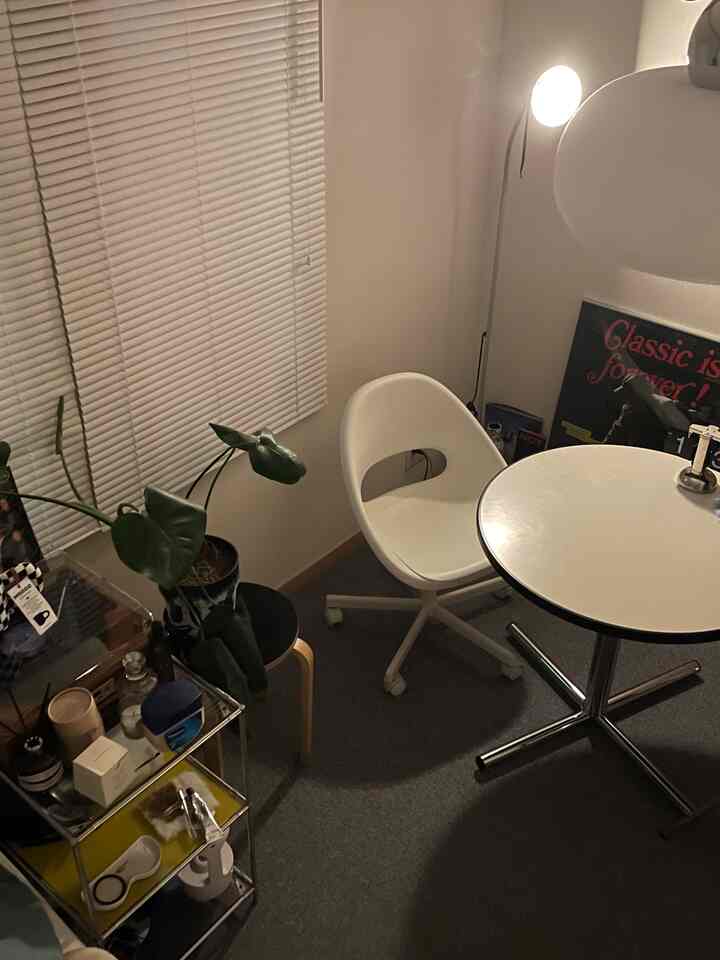 白とグレーのトーンのコンパクトで狭い一人用ホームオフィス、スツールと植物が調和したシンプルなインテリア