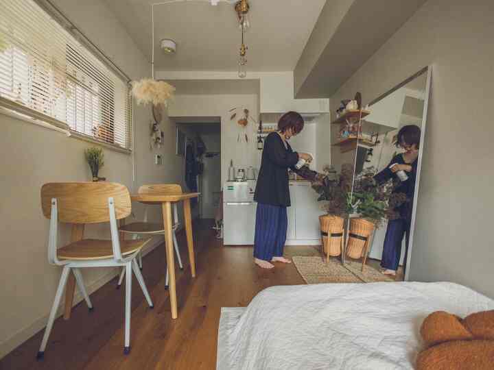 Beige and wood-tone studio apartment featuring small dining table, large mirror, and plants with cozy atmosphere