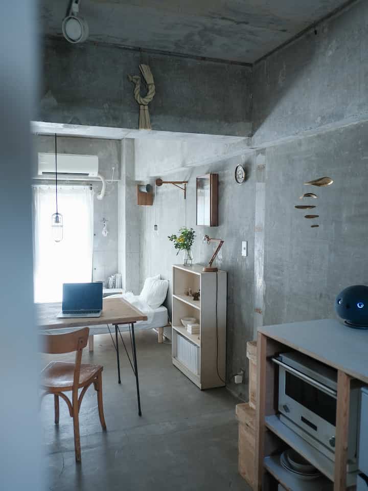 Gray concrete walls with white sofa bed and natural wood table in a small natural-style living room