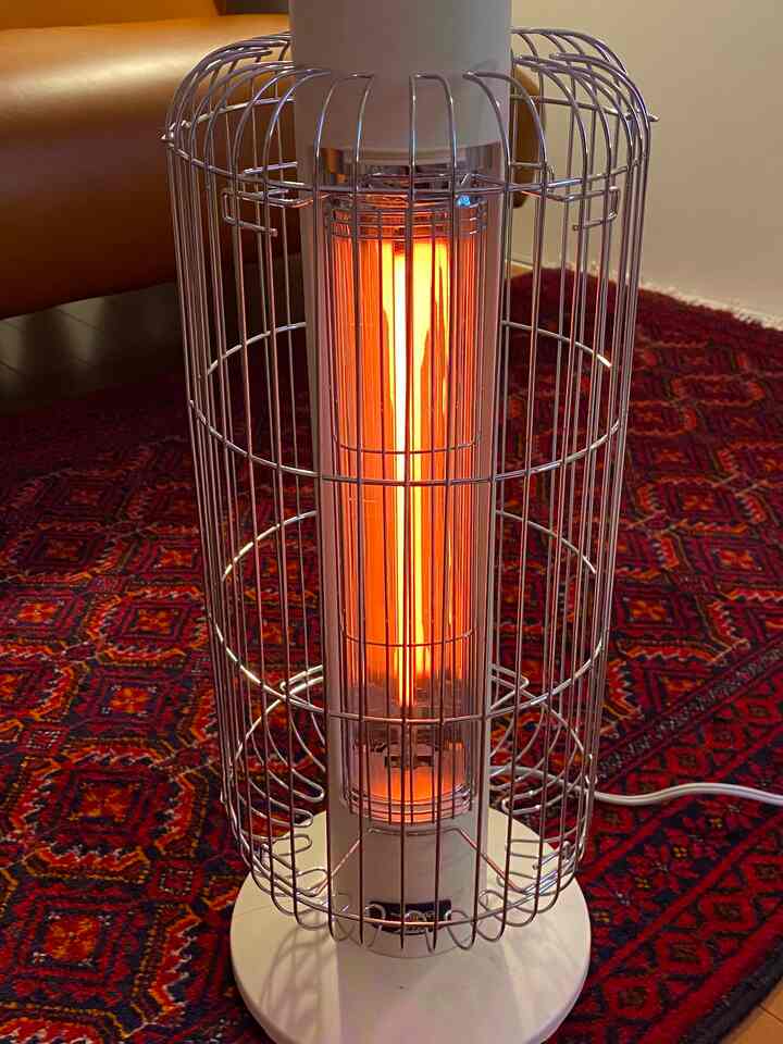 暖かみのある赤いカーペットの上に電気ヒーターが置かれたワンルーム、自然な色調の雰囲気あるインテリア