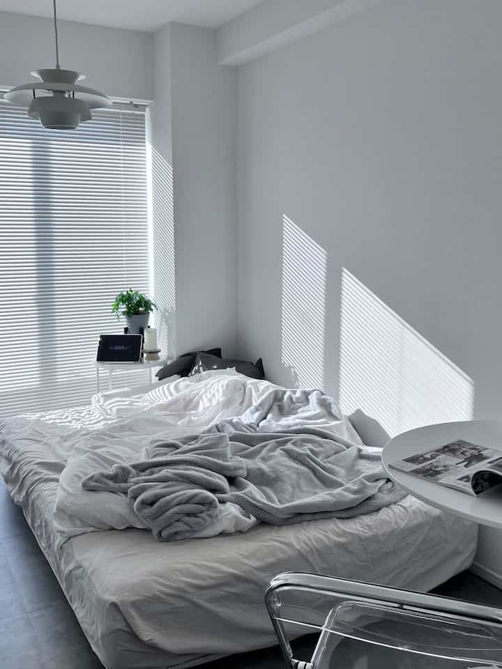 White-toned bedroom featuring a transparent chair and simple furniture in a modern setting