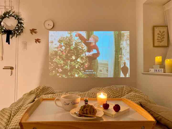 Cozy studio bedroom with warm brown and white tones, featuring a projector screen and Christmas decorations