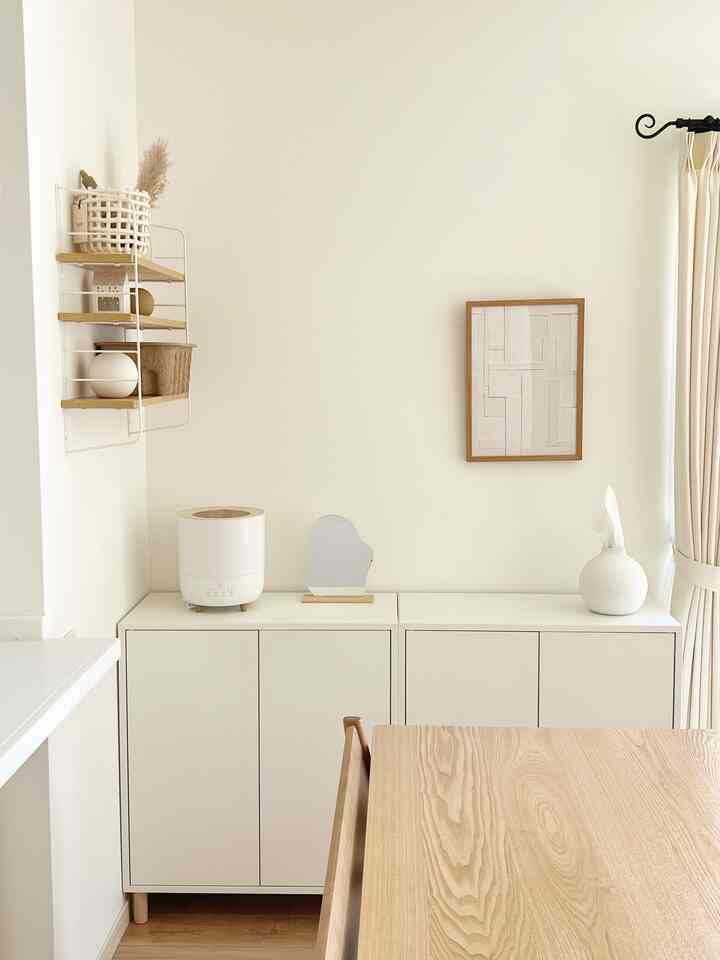 白と木目調のダイニングルーム、ミニマルなダイニングテーブルと収納が配置された清潔感のある空間