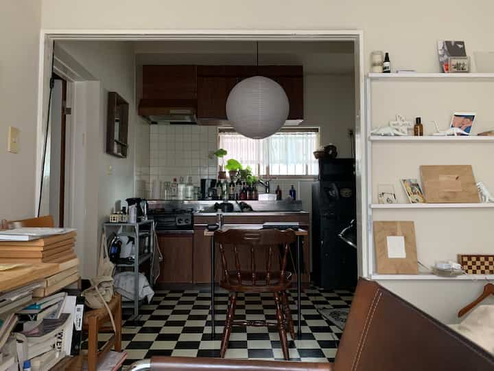 Brown-toned kitchen and living area with compact retro-style space featuring checkerboard floor and pendant lighting